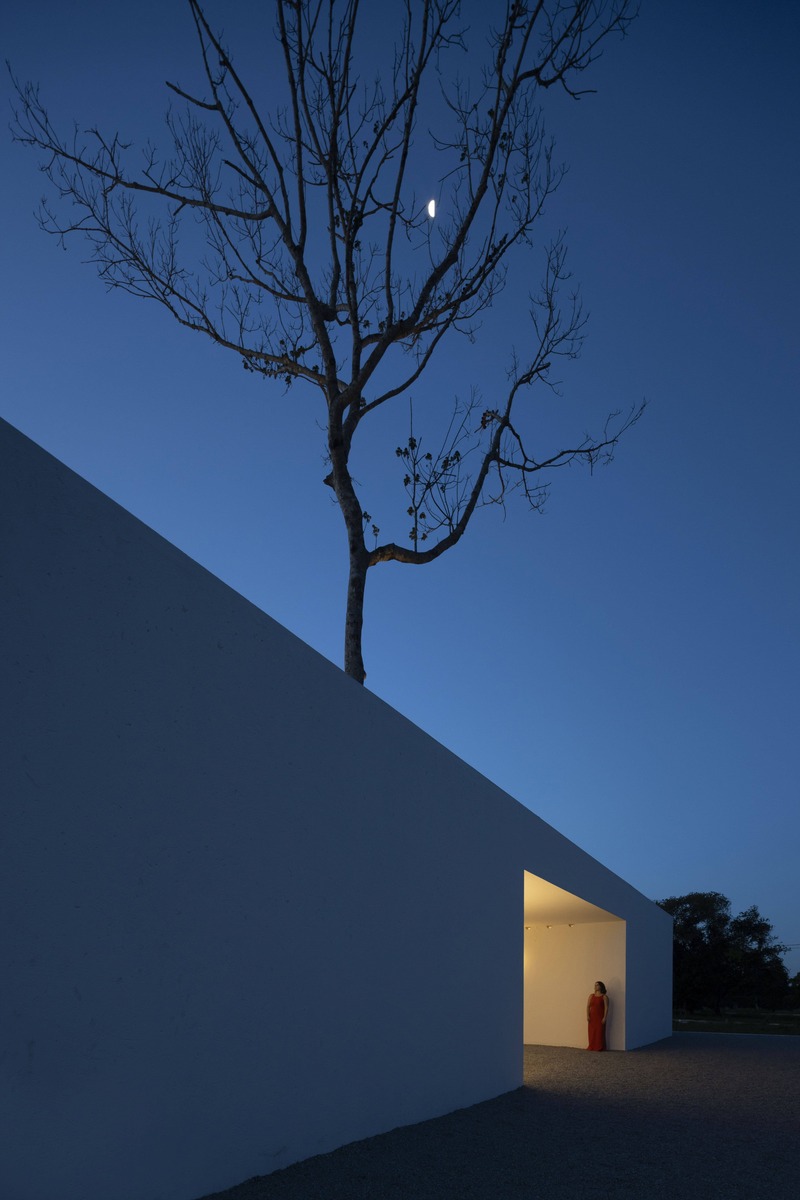 white perforated cubic facade wraps hybrid home and studio around a tree in brazil - 10