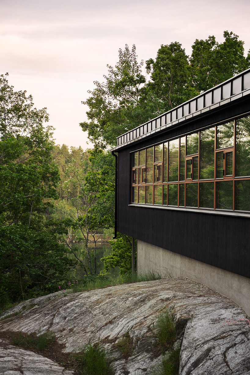 andrénfogelström nestles wooden villa with copper-clad bridge in swedish archipelago