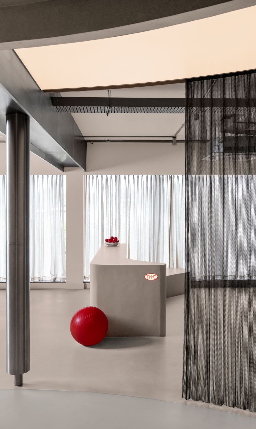 Sala de exposición de formas texturizadas de hormigón y acero en la India organizada en un ciclo continuo