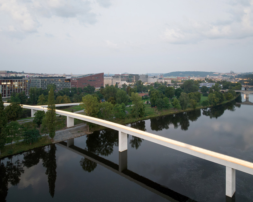 sleek concrete pedestrian bridge spans the vltava river in prague