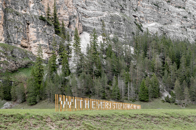 hundreds of wooden poles make up anamorphic installation spreading across italian hillside