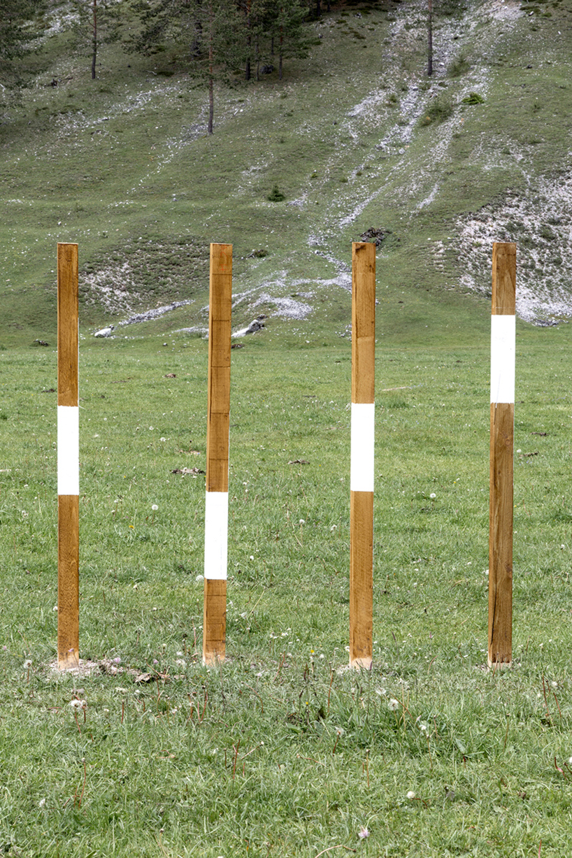 hundreds of wooden poles make up anamorphic installation spreading across italian hillside