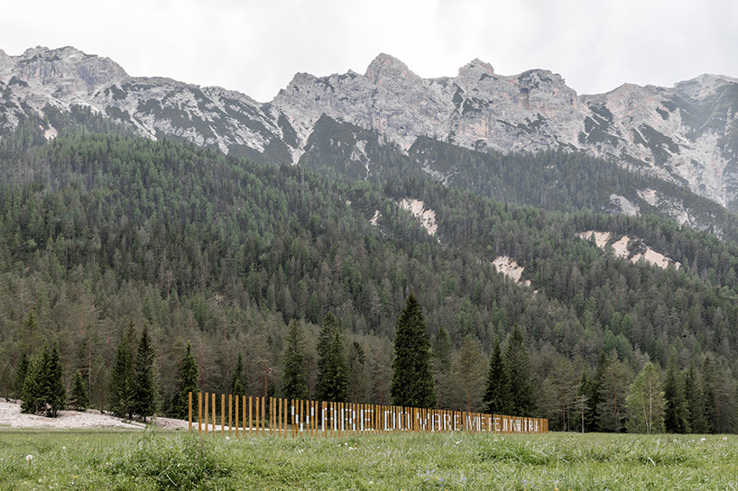 hundreds of wooden poles make up anamorphic installation spreading across italian hillside