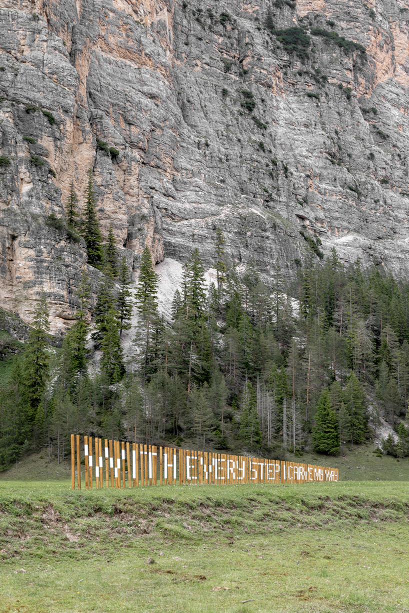 hundreds of wooden poles make up anamorphic installation spreading across italian hillside