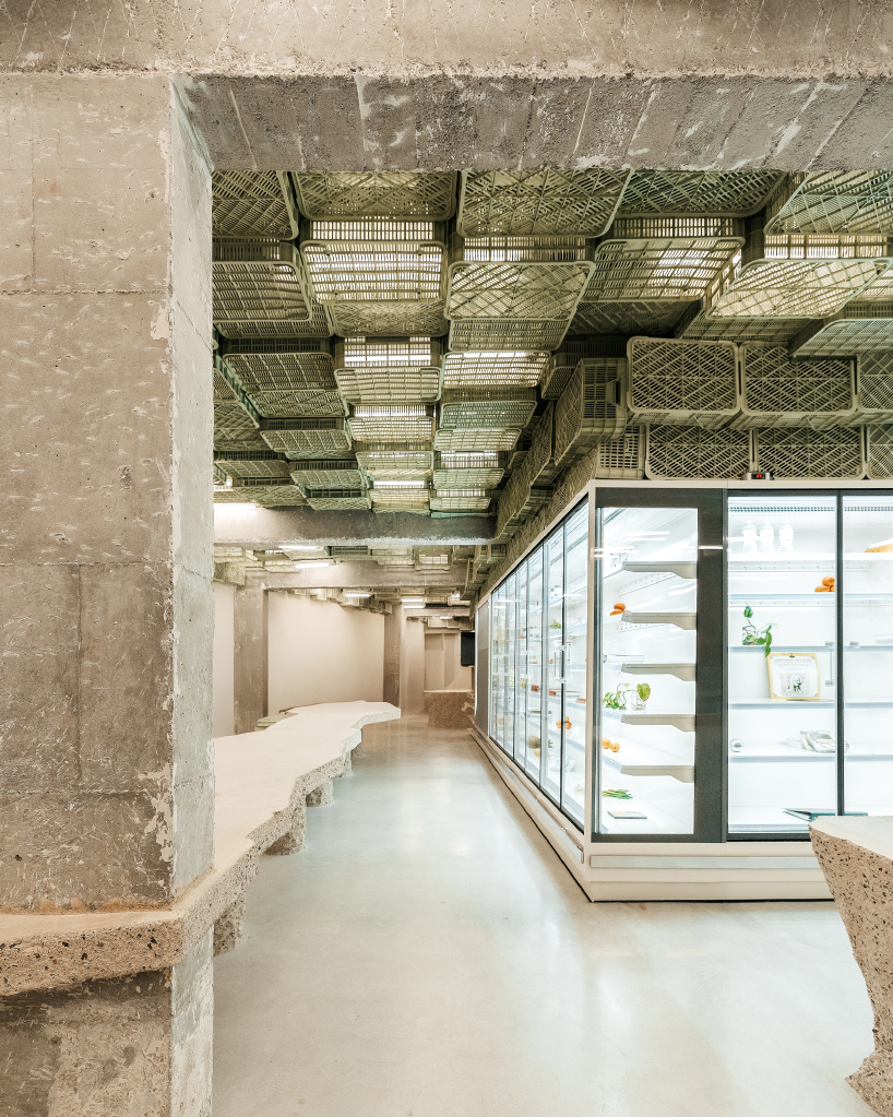 ceiling of recycled plastic crates expands over brutalist supermarket in mallorca