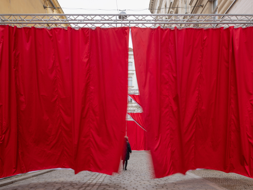 red and white curtains transform czech historic center’s pathways into christmas installation