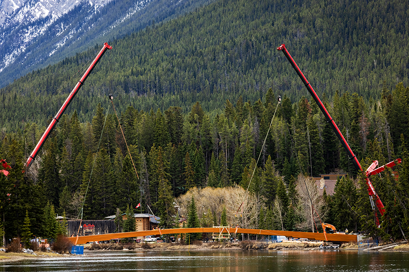 nancy pauw pedestrian bridge's timber arch spans over bow river in canada