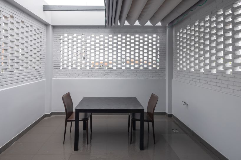 folding teak shutters weave light and nature into pham trung's narrow home in vietnam