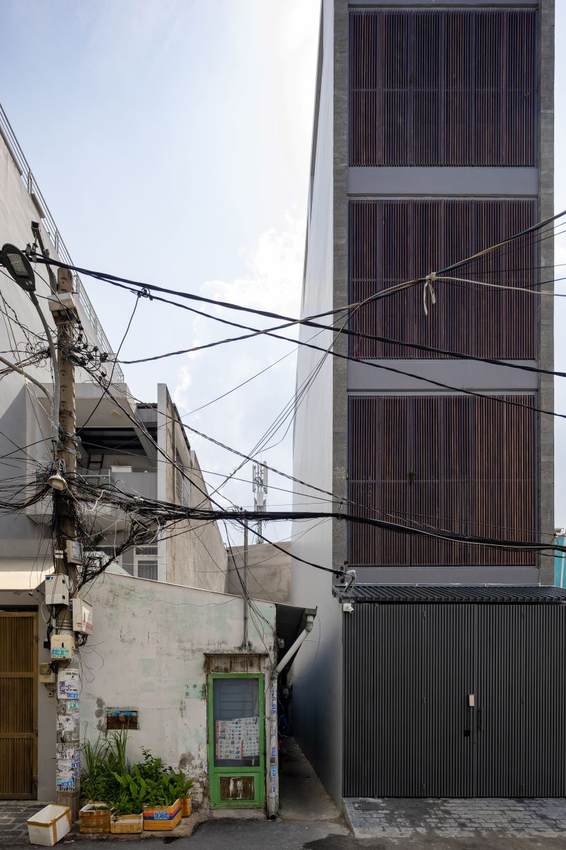 folding teak shutters weave light and nature into pham trung's narrow home in vietnam