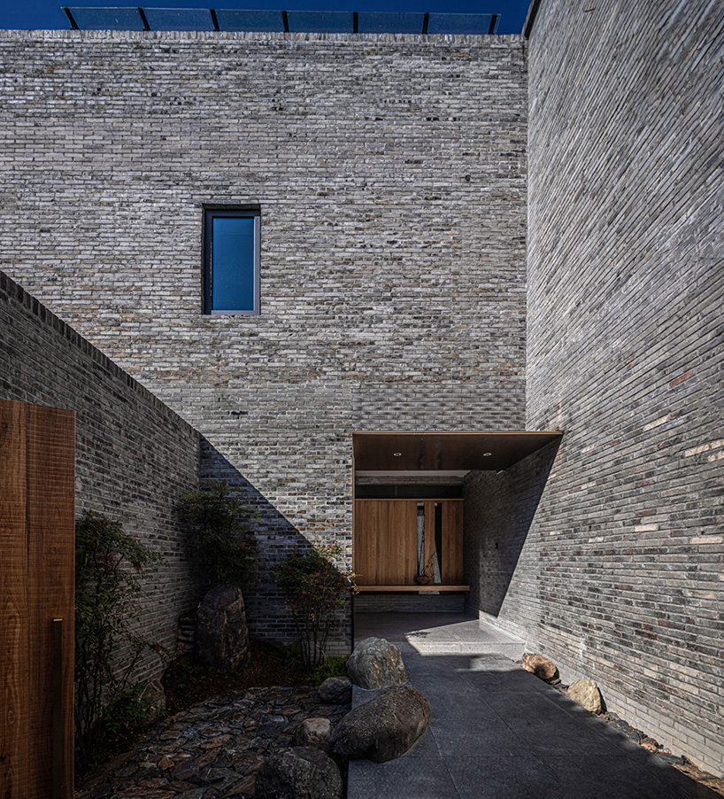 elongated gray brick cladding envelops hotel in chinese ancient village