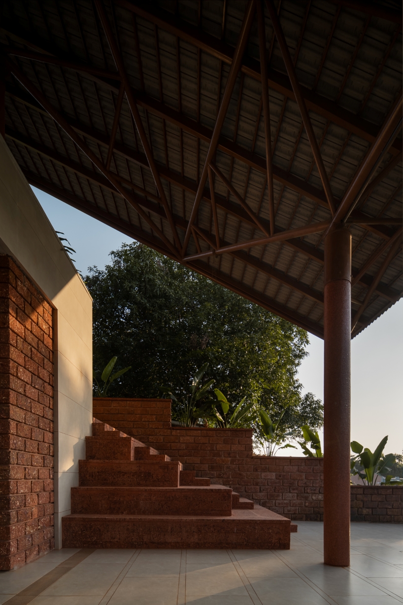 gabled roof floats over gathering pavilion’s brick stepped plinths in india - 9