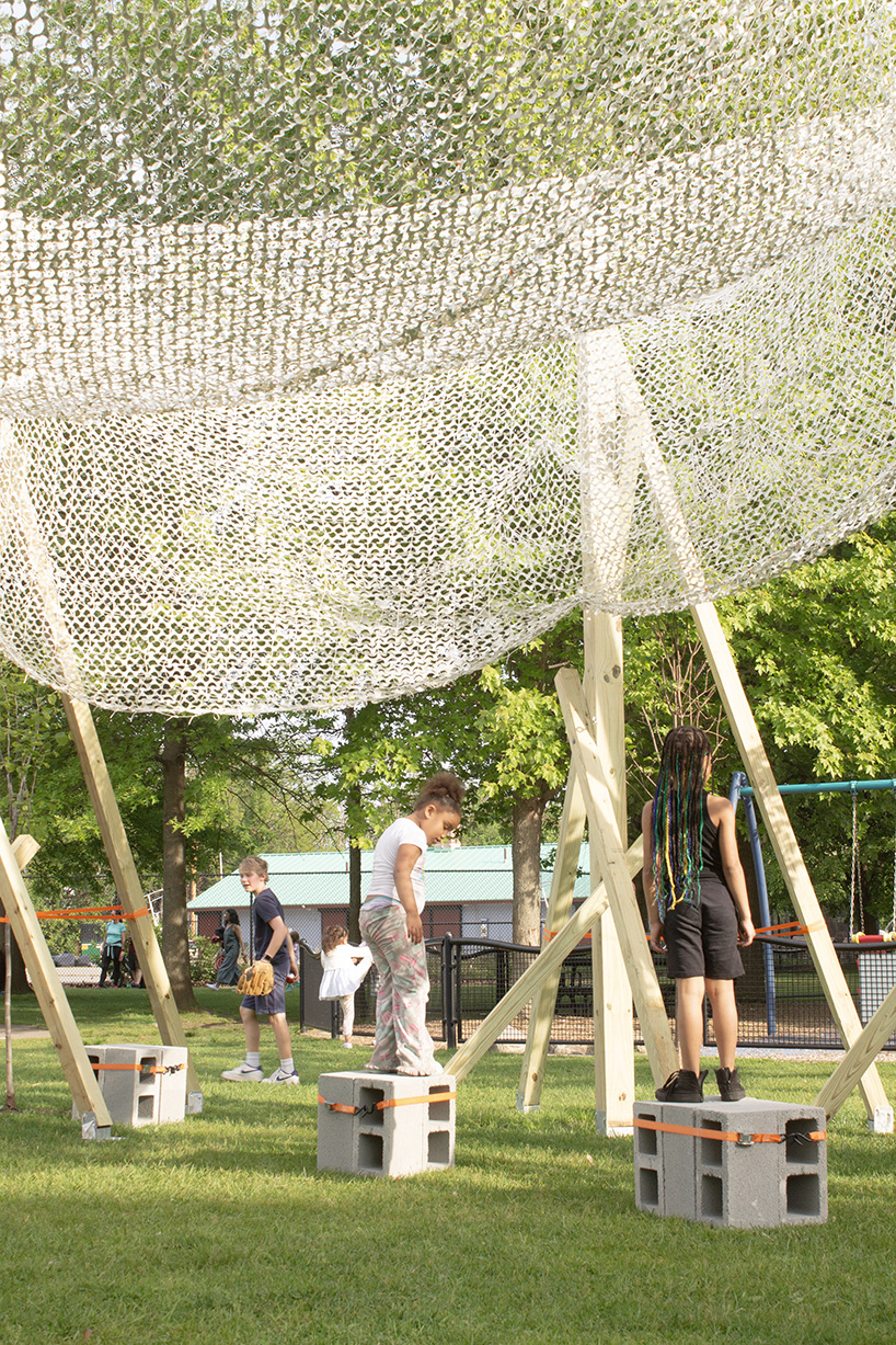 vanishing community room by alsar atelier uses tree stakes and textile canopies for shading