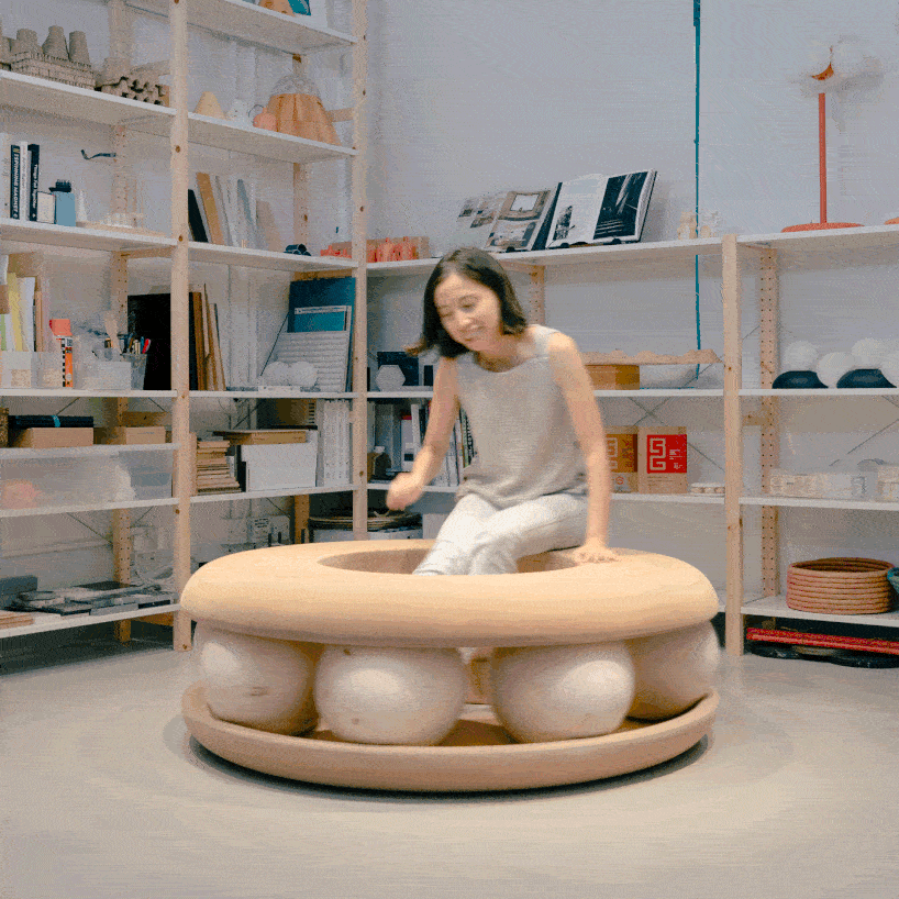 Bolas de madera ponen en movimiento un banco con forma de donut en un estudio junto al canal