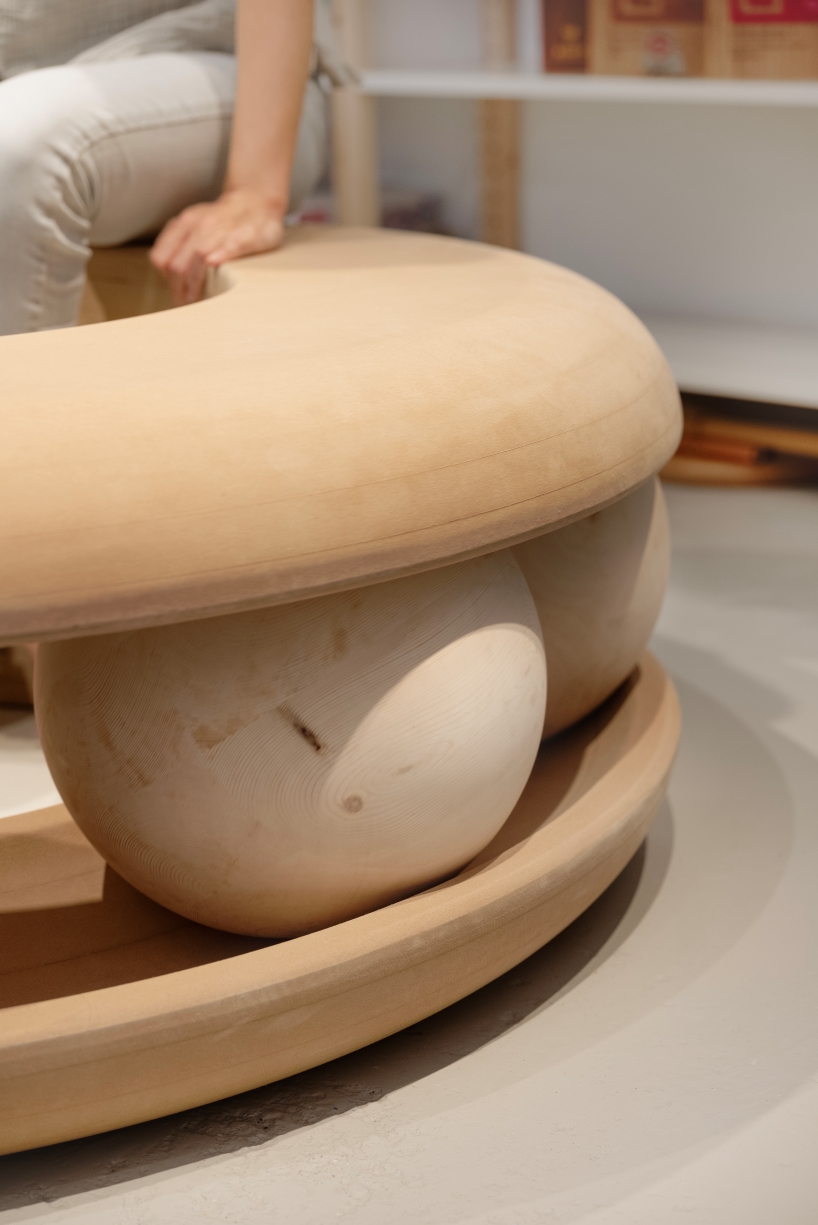 Bolas de madera ponen en movimiento un banco con forma de donut en un estudio junto al canal