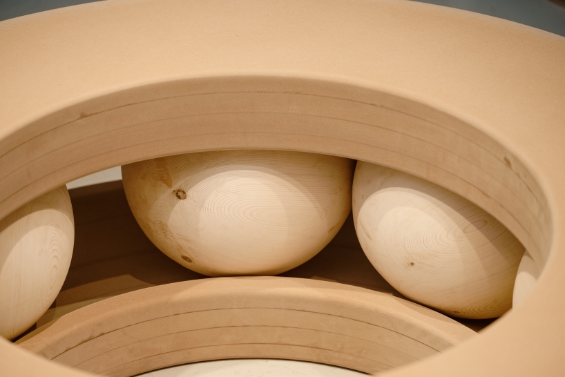 Bolas de madera ponen en movimiento un banco con forma de donut en un estudio junto al canal