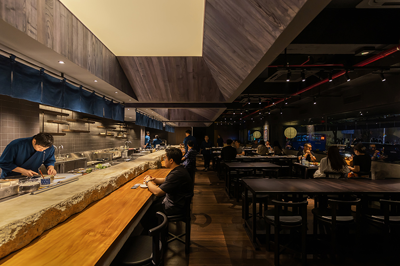 indigo fabric partitions float above sculpted concrete counters in rokusho bar by inrestudio