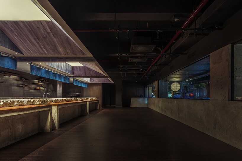 indigo fabric partitions float above sculpted concrete counters in rokusho bar by inrestudio