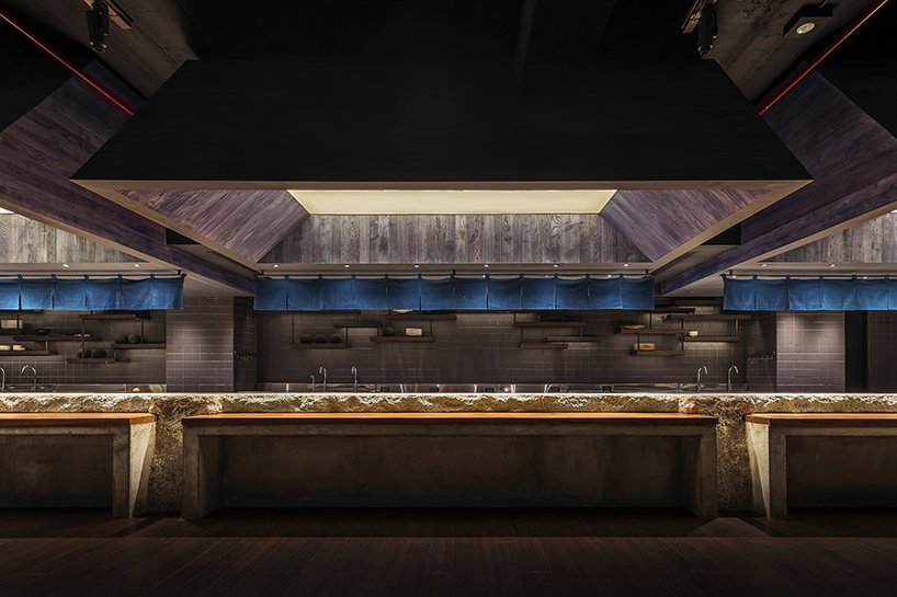 indigo fabric partitions float above sculpted concrete counters in rokusho bar by inrestudio