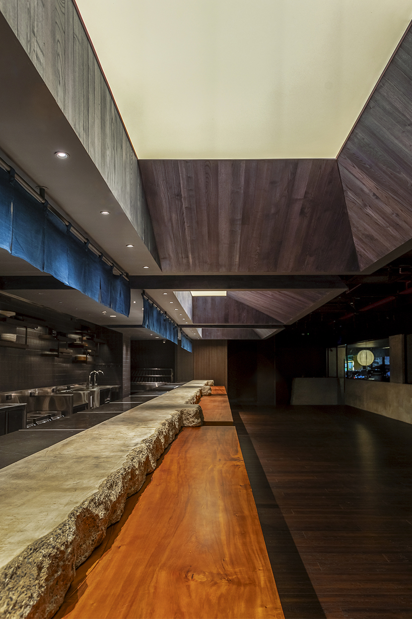 indigo fabric partitions float above sculpted concrete counters in rokusho bar by inrestudio