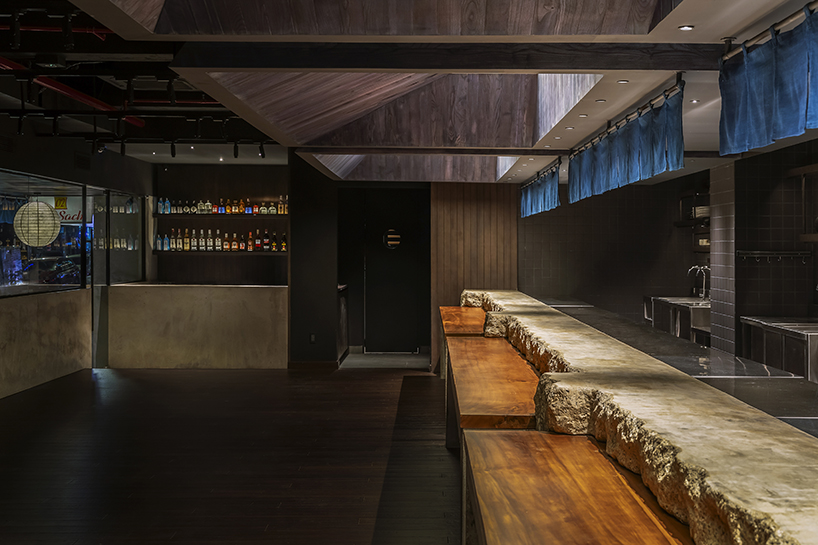 indigo fabric partitions float above sculpted concrete counters in rokusho bar by inrestudio