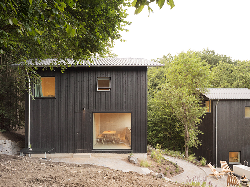 dark timber holiday cabins immerse guests in the stillness of remote german forest