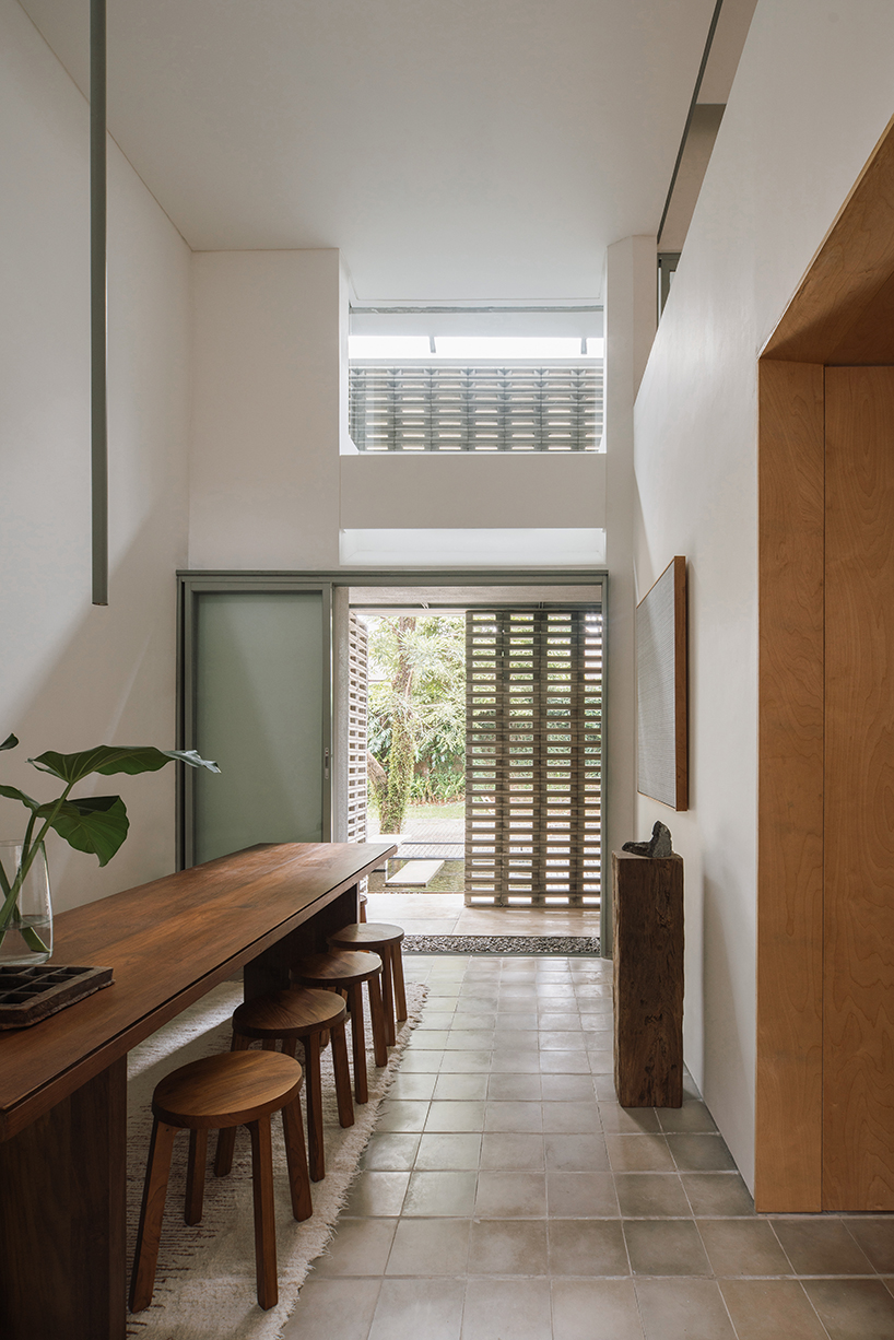 interlocking spaces behind perforated brick facade turn home into an office by dhanie & sal in indonesia