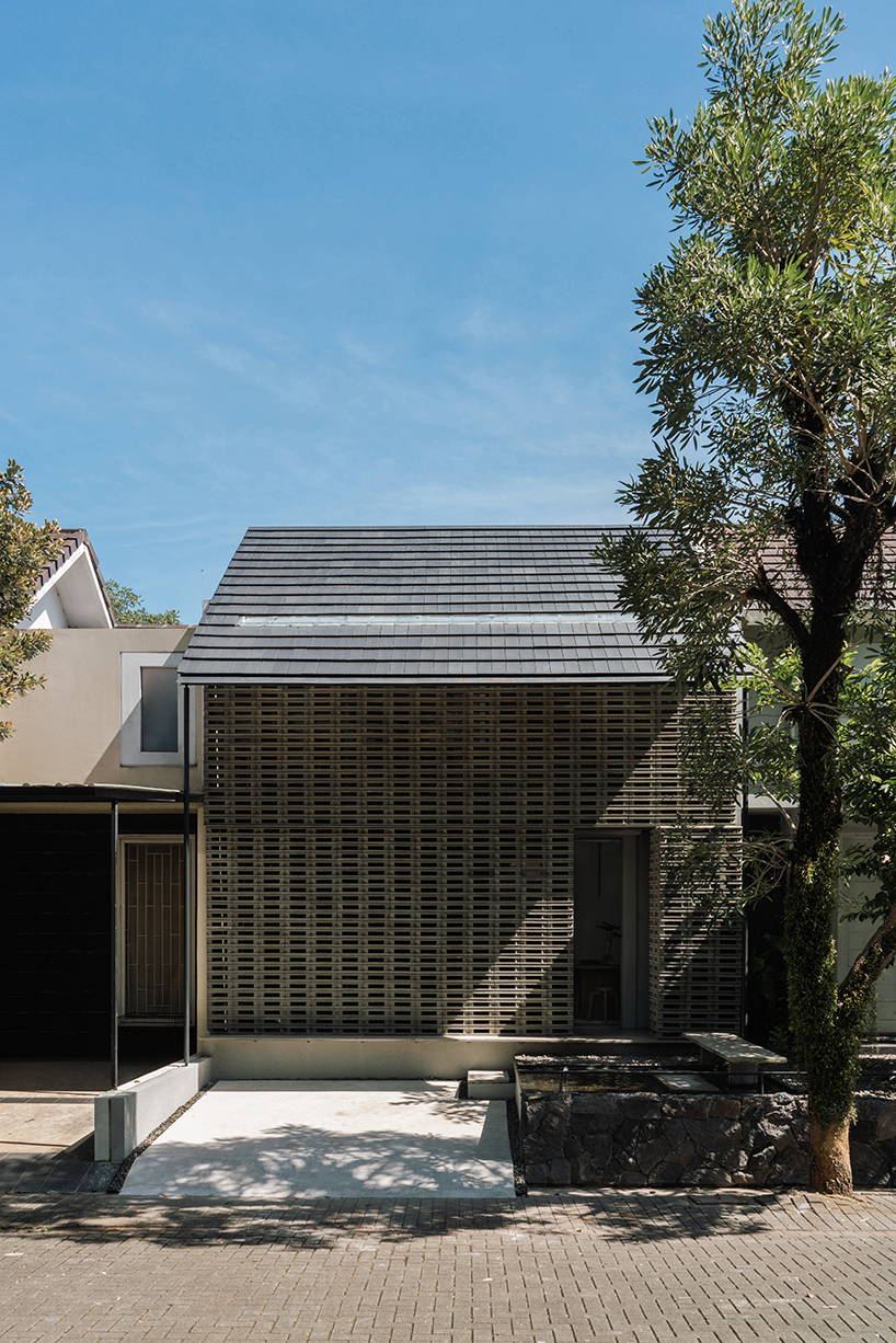 interlocking spaces behind perforated brick facade turn home into an office by dhanie & sal in indonesia