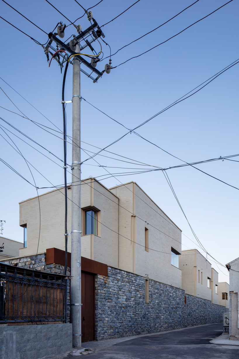eight interconnected stone-clad buildings compose long circle B&B in beijing