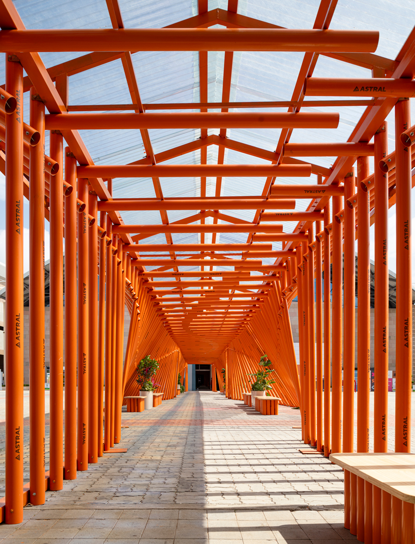 nudes' flow pavilion forms sinuous steel-pipe bridge between two exhibition halls in india