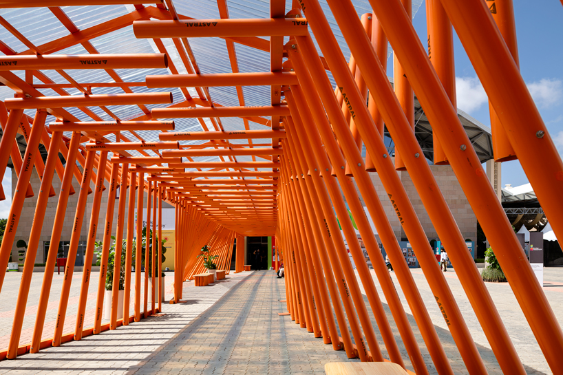 nudes' flow pavilion forms sinuous steel-pipe bridge between two exhibition halls in india