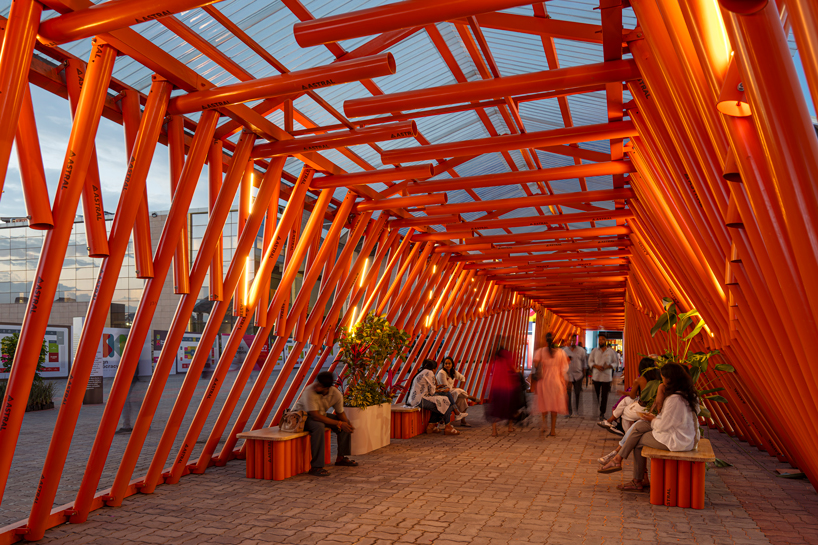 nudes' flow pavilion forms sinuous steel-pipe bridge between two exhibition halls in india