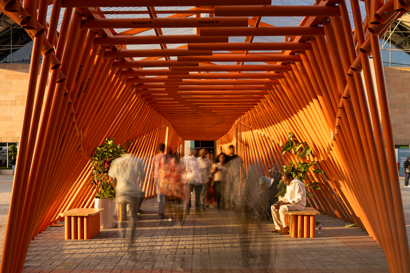 nudes' flow pavilion forms sinuous steel-pipe bridge between two exhibition halls in india