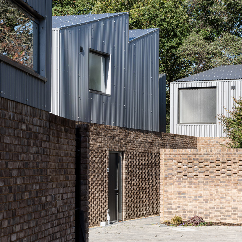 'upside-down' forest houses with sawtooth roofs rise from a brick plinth in london