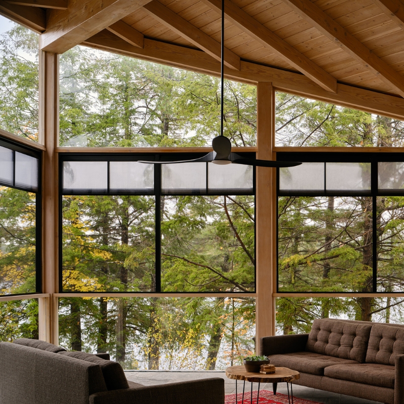 wooden cottage's jagged overhangs hover above lake landscape in canada