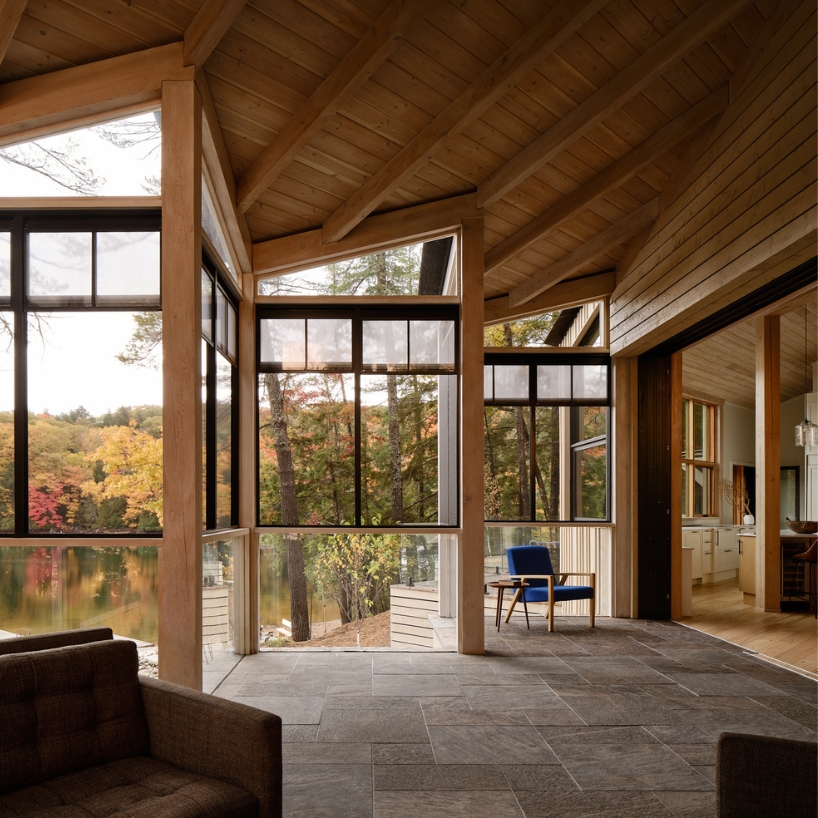 wooden cottage's jagged overhangs hover above lake landscape in canada
