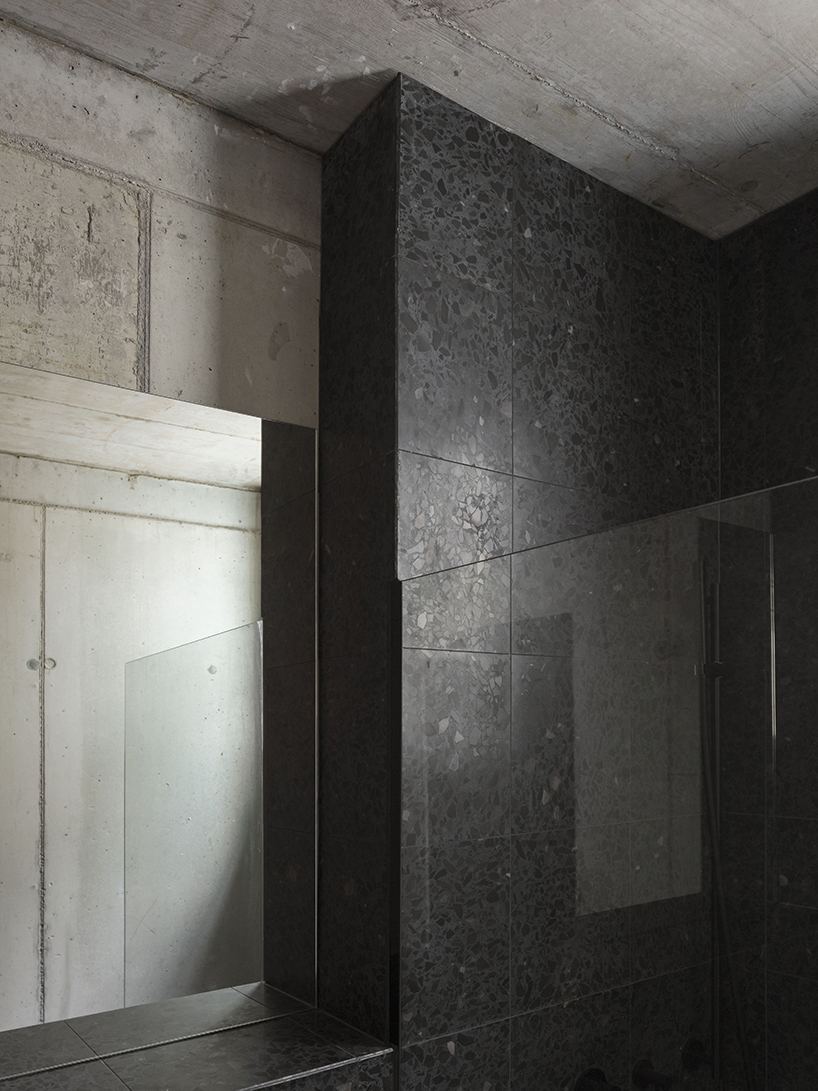 black charred timber cladding envelops twin gabled houses with one pillar in munich