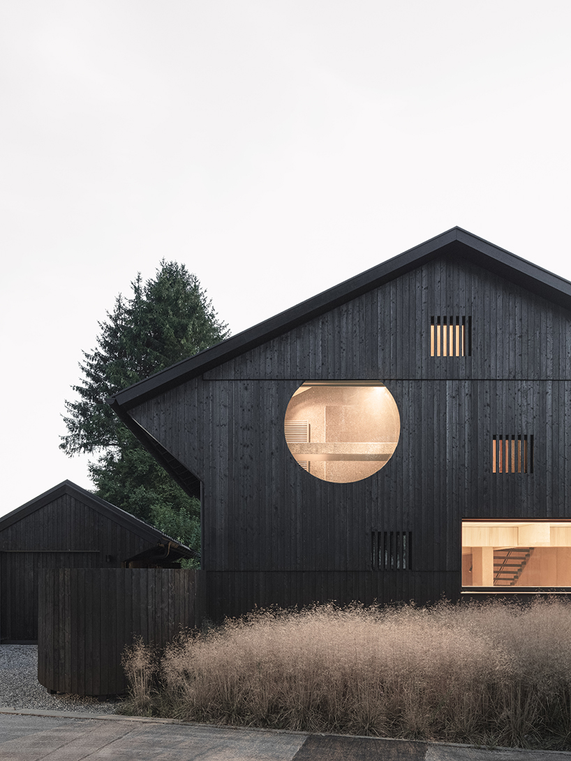 black charred timber cladding envelops twin gabled houses with one pillar in munich