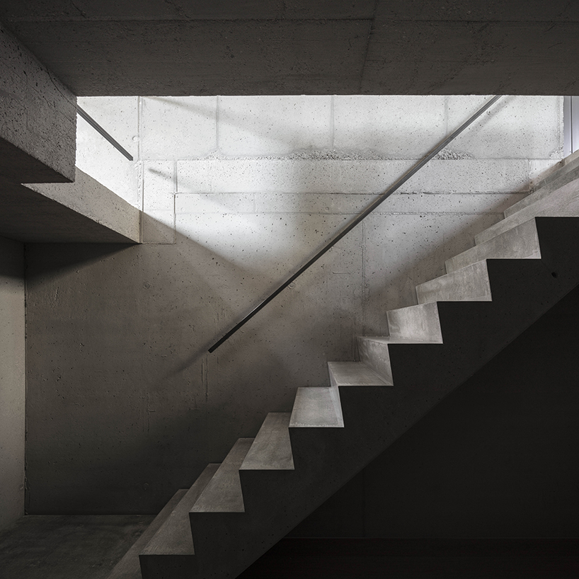 black charred timber cladding envelops twin gabled houses with one pillar in munich