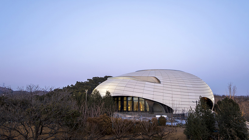 wutopia lab carves soft white caving interiors for pebble-shaped mountain hotel in china