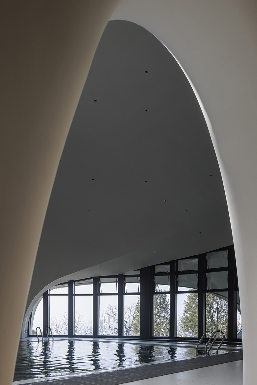 wutopia lab carves soft white caving interiors for pebble-shaped mountain hotel in china