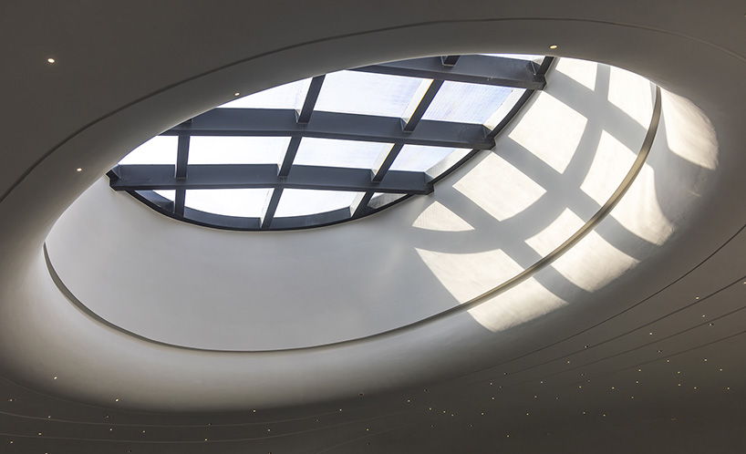 wutopia lab carves soft white caving interiors for pebble-shaped mountain hotel in china