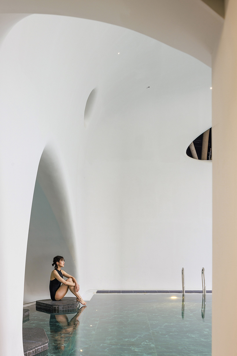 wutopia lab carves soft white caving interiors for pebble-shaped mountain hotel in china