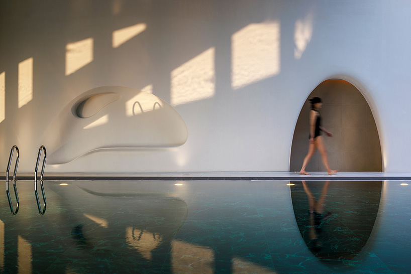 wutopia lab carves soft white caving interiors for pebble-shaped mountain hotel in china