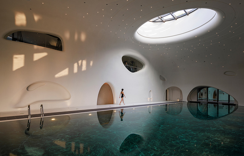 wutopia lab carves soft white caving interiors for pebble-shaped mountain hotel in china