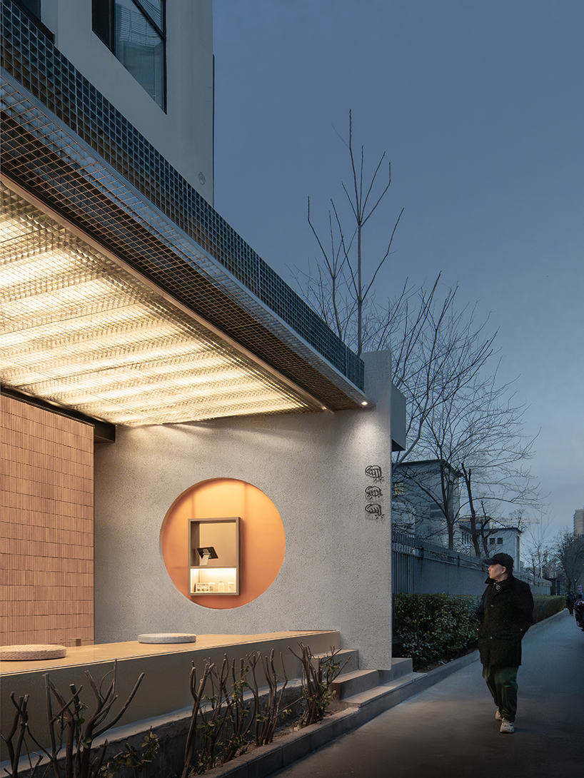 lantern-like lighting shines through suspended metal grid within tea pavilion in beijing
