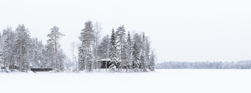 ecological wooden cabin nestles in rural finland's lakeside setting