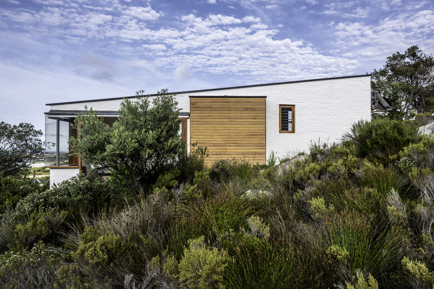 discreet white brick-built cottage perches on south african hillside