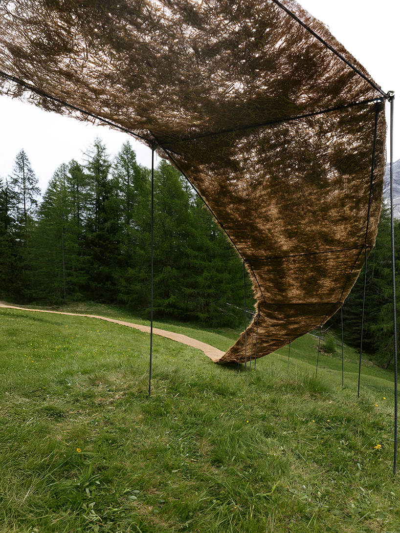 hay bales unroll into trace of land installation across alpine terrain in italy