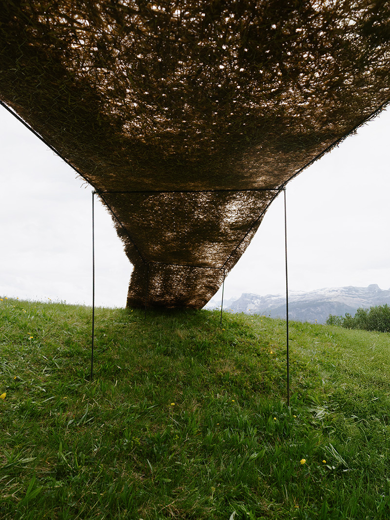 hay bales unroll into trace of land installation across alpine terrain in italy