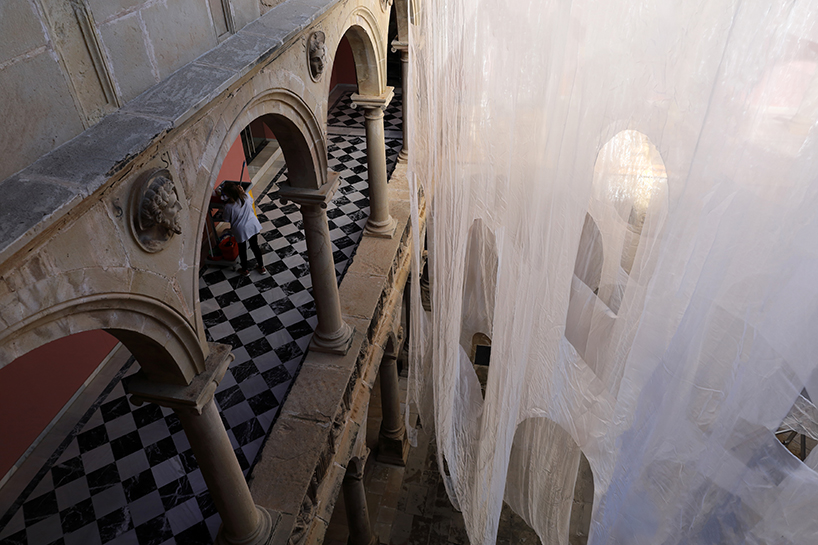 translucent organza curtains float within renaissance arched courtyard in spain